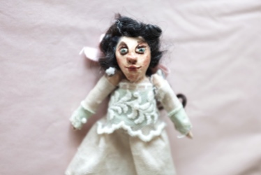miniature art doll of a victorian girl in green and pink with black curly hair