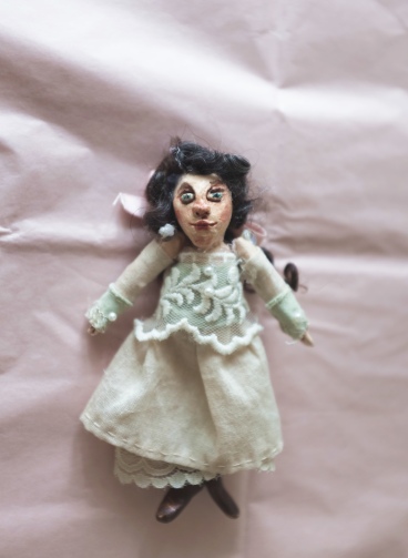 miniature art doll wearing a white and green victorian lace dress