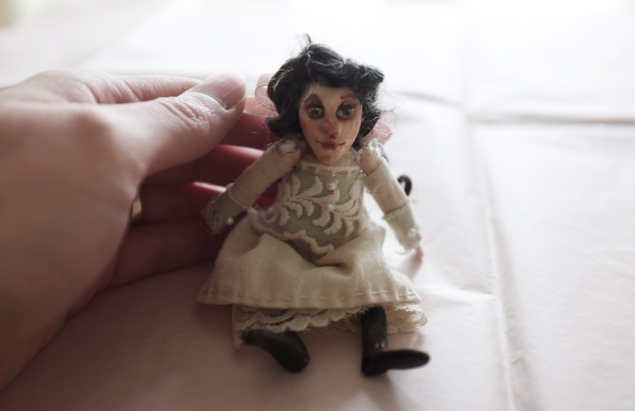 close up of a hand holding a miniature art doll of a victorian girl, to show scale