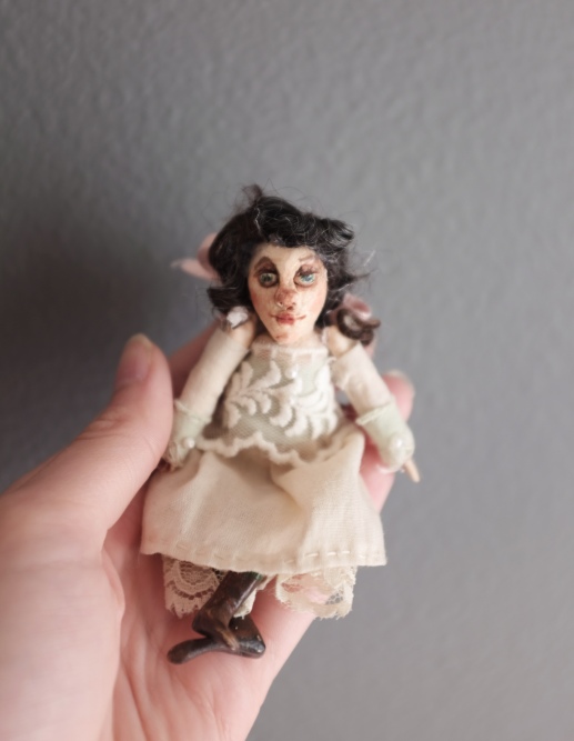 hand holding a miniature victorian doll