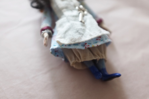 close up showing stitching and clothing of a miniature doll