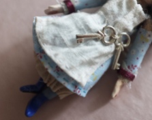 close up of a miniature doll holding a tiny ring of keys