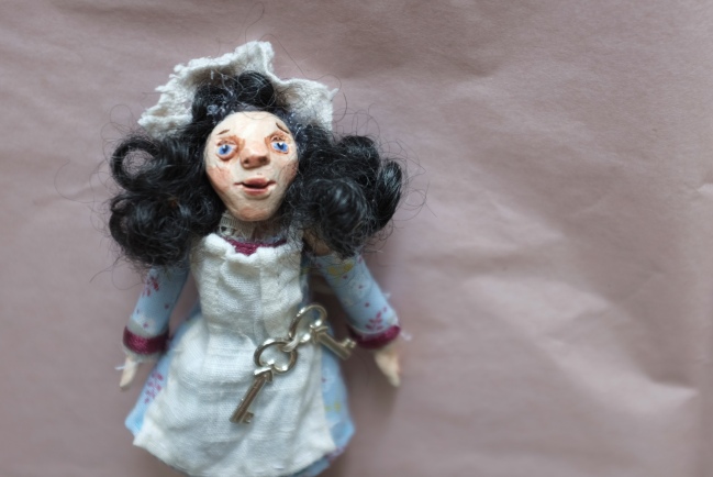 miniature art doll dressed as a maid, with lace cap and curly hair