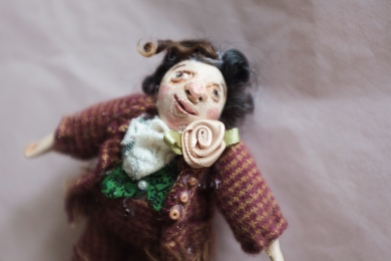 miniature art doll of a victorian gentleman with curly hair and a rose