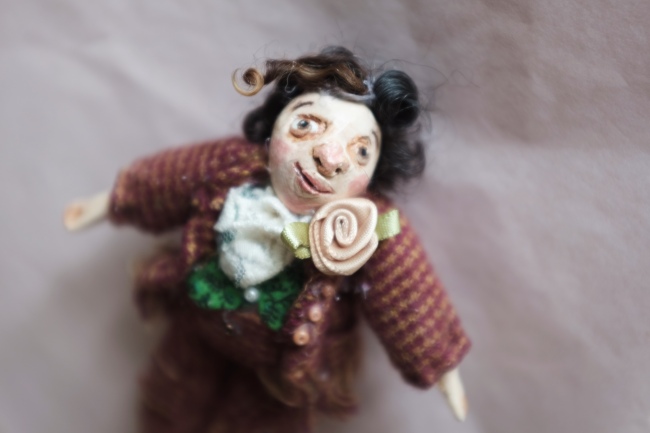 miniature doll of a victorian gentleman wearing a suit with a rose