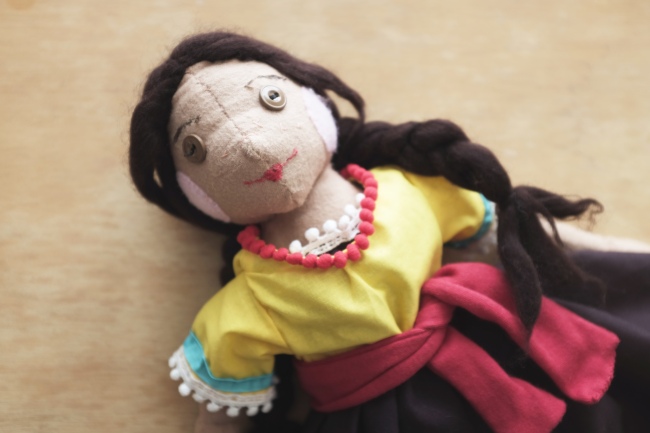 cloth children's doll with two braids wearing a Mexican dress