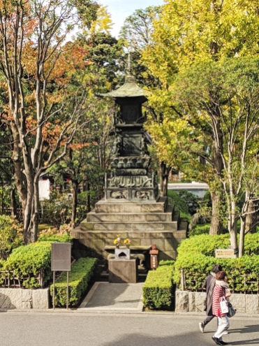 stone tower monument or shrine surrounded by fall foliage in tokyo